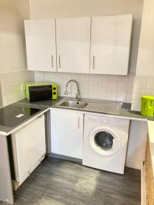 a kitchen with a sink and a washing machine at Goswell Central Apartment by DC London Rooms in London