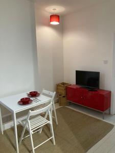 uma sala de estar com uma mesa branca e um armário vermelho em Goswell Central Apartment by DC London Rooms em Londres