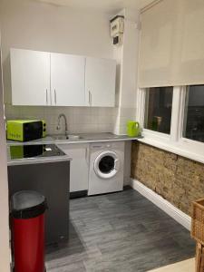 a kitchen with a sink and a washing machine at Goswell Central Apartment by DC London Rooms in London