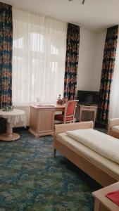 ein Hotelzimmer mit 2 Betten, einem Schreibtisch und einem Fenster in der Unterkunft Pension Fürstenhof in Bad Elster
