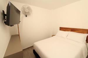 a small bedroom with a bed and a tv at Hotel Pajara Pinta in Cali