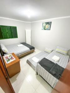 a room with two beds and a table in it at Apto com churrasq em Monte Castelo-Campo Grande MS in Campo Grande