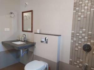 uma casa de banho com um WC, um lavatório e um espelho. em Palmeiral BeachVilla em Calangute