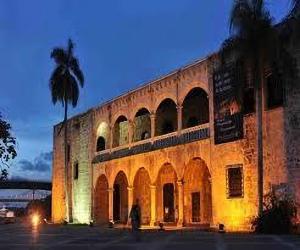 a large building with a palm tree in front of it at Hotel Colonial Blanco in Santo Domingo