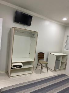 um quarto com um espelho e uma cadeira e uma televisão em GUARANY HOTEL PONTA PORÃ em Ponta Porã