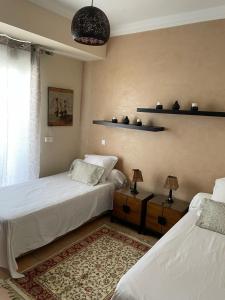 a bedroom with two beds and two lamps and a rug at Les Jardins d'Asilah in Asilah +59 photos