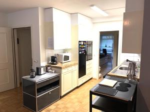 una cocina con armarios blancos y electrodomésticos negros en XL City Center Apartment-contactless check-in Netflix Included en Basilea