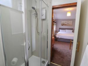a bathroom with a shower and a bedroom at Old School Muncaster House in Ravenglass