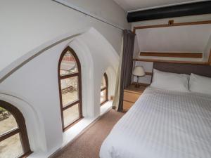 a bedroom with a bed and two windows at Old School Muncaster House in Ravenglass