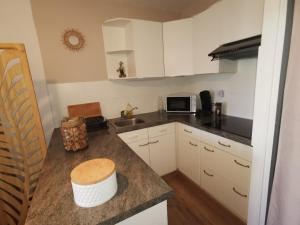 ル・バルカレスにあるAppartement Cosy sur la Presqu'île de Cap Coudalere avec terrasse et piscine chauffée jusqu'à fin octobre, aire de jeux d'enfants, parkingの白いキャビネットとカウンタートップを備えたキッチン