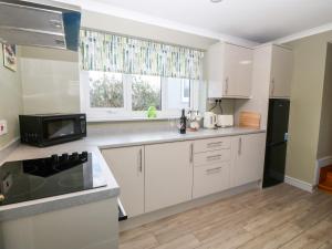 uma cozinha com armários brancos e uma janela em Cedars em Holyhead