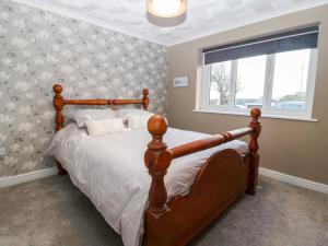 a bedroom with a bed and a window at Cedars in Holyhead