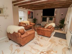 a living room with leather furniture and a marble floor at Donni Hall Cottage in Chathill