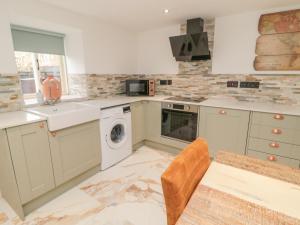 a kitchen with a washer and a sink and a dishwasher at Donni Hall Cottage in Chathill