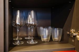 four wine glasses and cups sitting on a shelf at Studio 501 in Kaunas