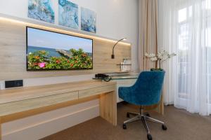 Habitación con escritorio, TV y silla azul. en HOTEL am STRAND en Kühlungsborn