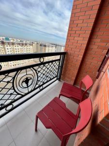 two red chairs sitting on a balcony with a view at Green Plaza-SeaView in Aktau