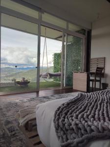 1 dormitorio con ventana grande y 1 cama con vistas en Sukha Resort, en La Calera