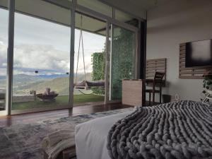 een slaapkamer met een bed en een groot glazen raam bij Sukha Resort in La Calera