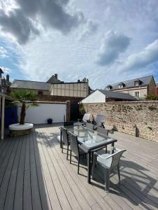 a patio with a table and chairs on a wooden deck at Bel appartement avec jardin au coeur d'Etretat in Étretat +21 photos