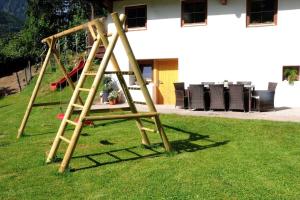 a wooden swing set in the grass in a yard at Ferienchalet Kreuzlauhof MAY-101 in Schwendau