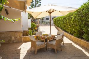 una mesa y sillas con una sombrilla en el patio en Villa Marsal, en Portocolom