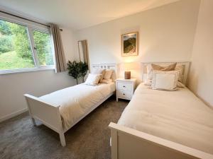 two beds in a room with two windows at Ciaran Cottage in Stron-fearnan