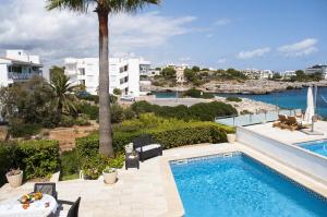 uma piscina com vista para o mar e para os edifícios em Villa Marsal em Porto Colom