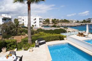 a pool with a view of the ocean and buildings at Villa Marsal in Portocolom