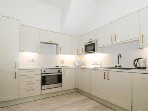 a white kitchen with white cabinets and a sink at St Saviours Reach in Dartmouth