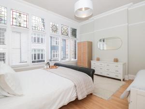 Dormitorio blanco con cama y ventanas en St Saviours Reach en Dartmouth