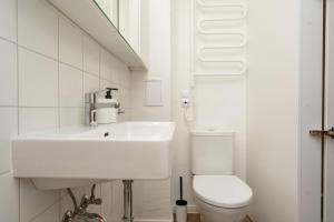Baño blanco con lavabo y aseo en Air Apartment 107 en Vilna