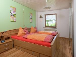 a bedroom with a bed with orange sheets and a window at Quiet apartment in Neukirch with private terrace in Furtwangen