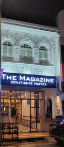 a large white building with a blue sign on it at The Magazine Boutique Hotel in George Town