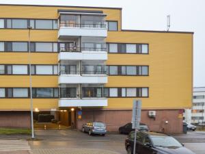 un edificio amarillo con coches estacionados en un estacionamiento en City Center Apartment, en Rovaniemi