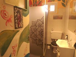 baño con aseo y lavamanos con una pintura en la pared en Hostel "La Casita Naranja" en El Bolsón