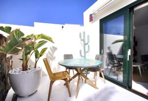 une terrasse avec une table, des chaises et une plante dans l'établissement Unique, Stylish & Calm Los Peces by the Sea, à Costa Teguise