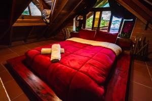 Hotel Le Chateau Guatape في غواتابيه: سرير احمر كبير في غرفة بها نوافذ