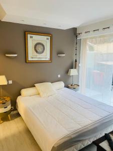 a large white bed in a bedroom with a window at 3 pièces terrasse, jardin in Cannes