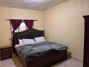 a bedroom with a large bed with a window at Delornya Complex in Freetown