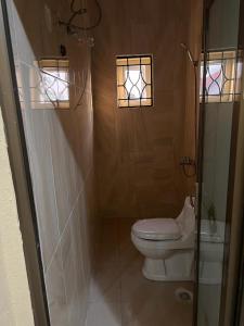 a bathroom with a toilet and two windows at Delornya Complex in Freetown