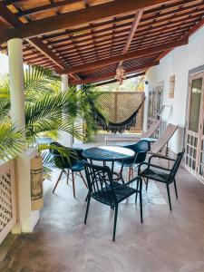 a patio with a table and chairs and a hammock at CASA ACAYU in São Miguel dos Milagres