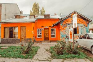 una casa naranja con graffiti a un lado. en Hostel "La Casita Naranja" en El Bolsón