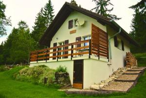a small white house with a large balcony at Le Joly Chalet in Saint-Imier