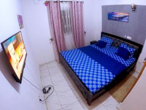 - une chambre avec un lit bleu et une télévision dans l'établissement TrierHouse, à Douala
