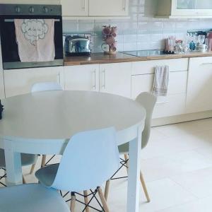a white kitchen with a white table and chairs at Bellevue Bungalow in Belfast