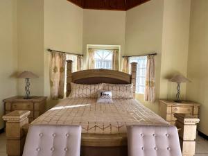 Un dormitorio con una cama grande con dos sillas. en A Luxurious 4-Bedroom Private Villa with Games Room, Theatre & Modern Art, en Montego Bay