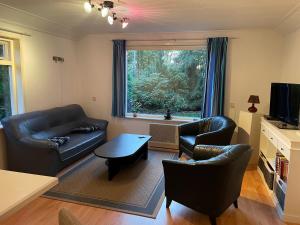 a living room with leather furniture and a large window at Boerenkiel Vakantiehuisjes in De Kiel