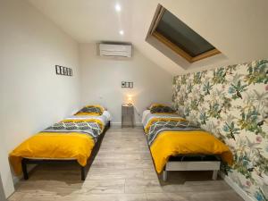 duas camas num pequeno quarto com lençóis amarelos em Duplex cosy - entre lacs et montagnes - Fêtes interdites em Fillinges
