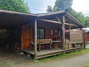 a house with a wooden porch with a table at Camping y cabañas Los Parrones in Valdivia